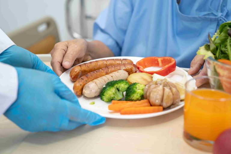 Healthcare worker serving food to an elderly patient.