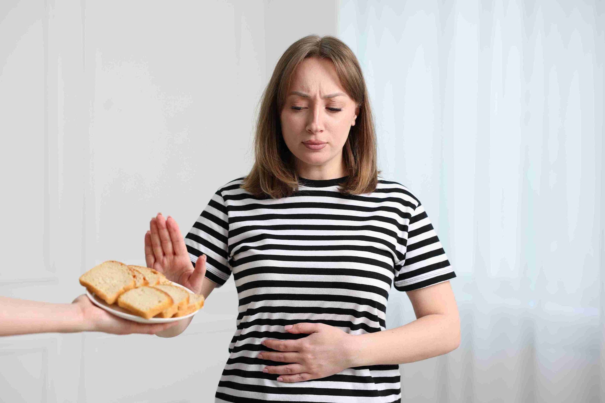 Woman refusing food, with hand on her stomach.