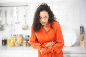 Woman holding her stomach in the kitchen.
