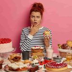 Woman with various food items looking confused.