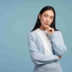 Asian woman with finger on chin, thinking about something.
