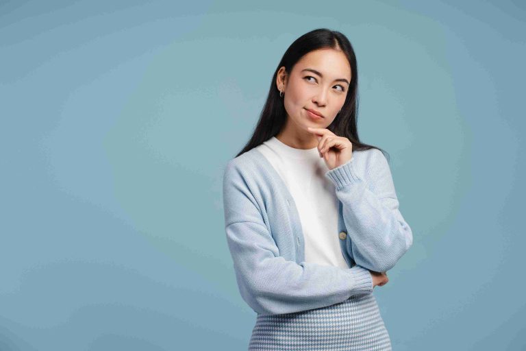 Asian woman with finger on chin, thinking about something.